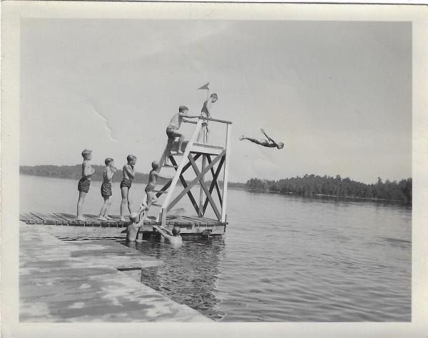 historic photo of boys jumping off diving board into lake